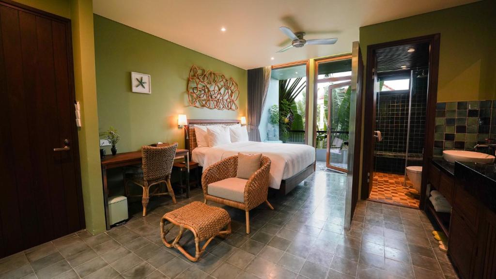 a bedroom with a bed and a table and chairs at CHiEM HoiAn - The Beachside Boutique Hotel & Villa in Hoi An