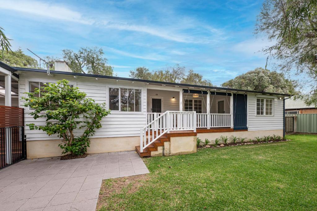 a white house with a porch and a yard at Summer Cottage in Dunsborough