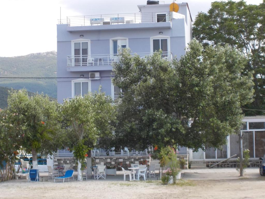 un bâtiment blanc avec des arbres devant lui dans l'établissement Hotel Prinos, à Prinos