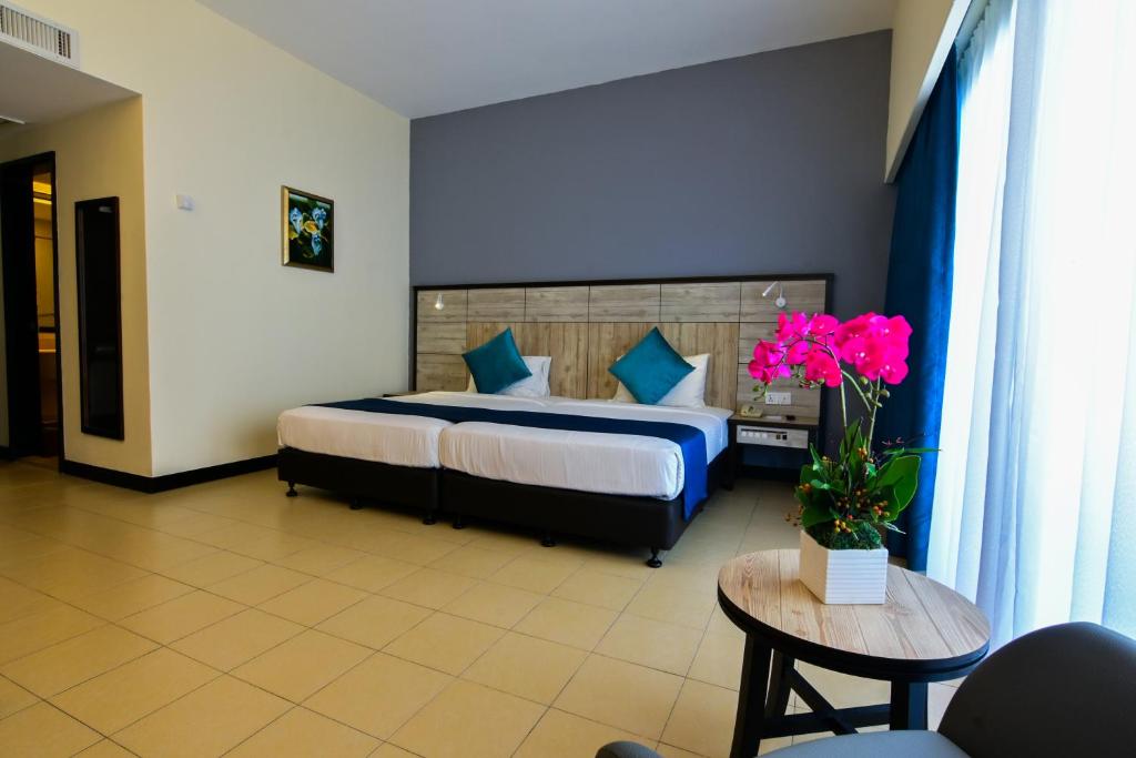 a hotel room with a bed and a table with flowers at Flamingo Hotel by the Beach, Penang in George Town