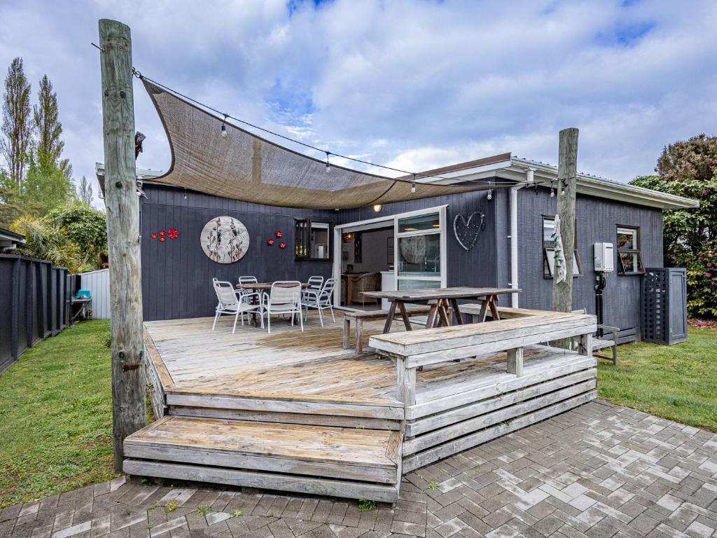 a house with a wooden deck with a table and chairs at Our Happy Place - Kinloch Holiday Home in Kinloch