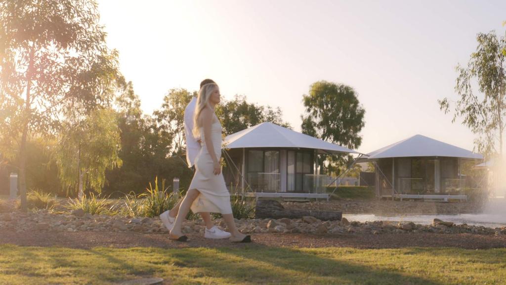 Une femme qui marche dans l'herbe devant une maison dans l'établissement Townsville Eco Resort, 