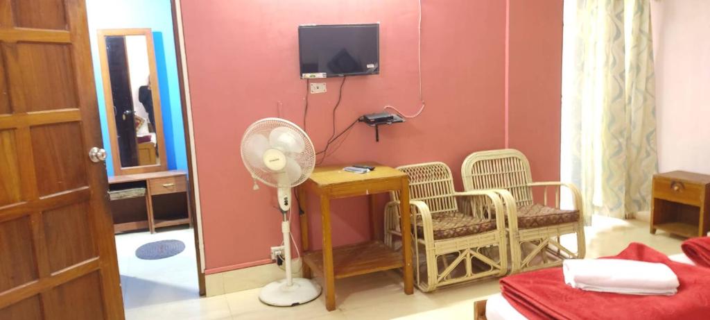 a room with a desk and chairs and a fan at Pine Shillong Guest House in Shillong