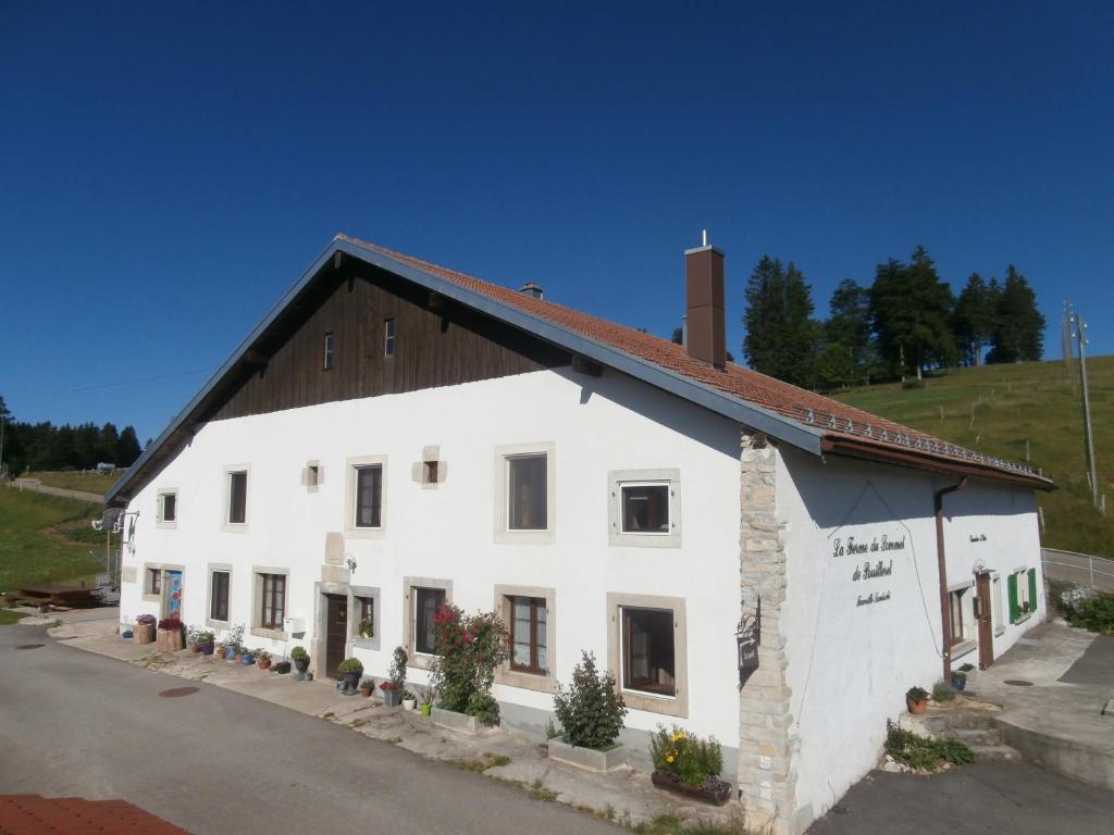 un bâtiment blanc avec un toit noir dans l'établissement B&B La Ferme De Pouillerel, à La Chaux-de-Fonds