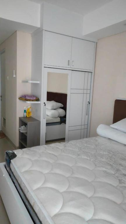 a white bedroom with a bed and white cabinets at Apartemen Skylounge Makassar in Manda