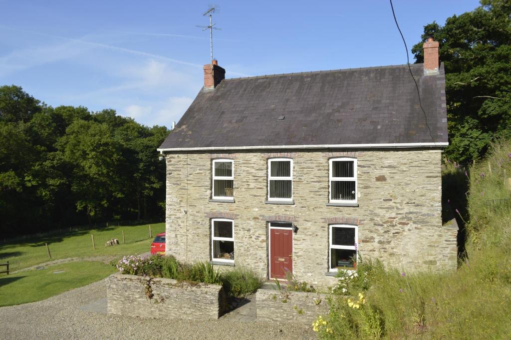 an old stone house with a red door at Troedyrhiw Bed & Breakfast in Cardigan