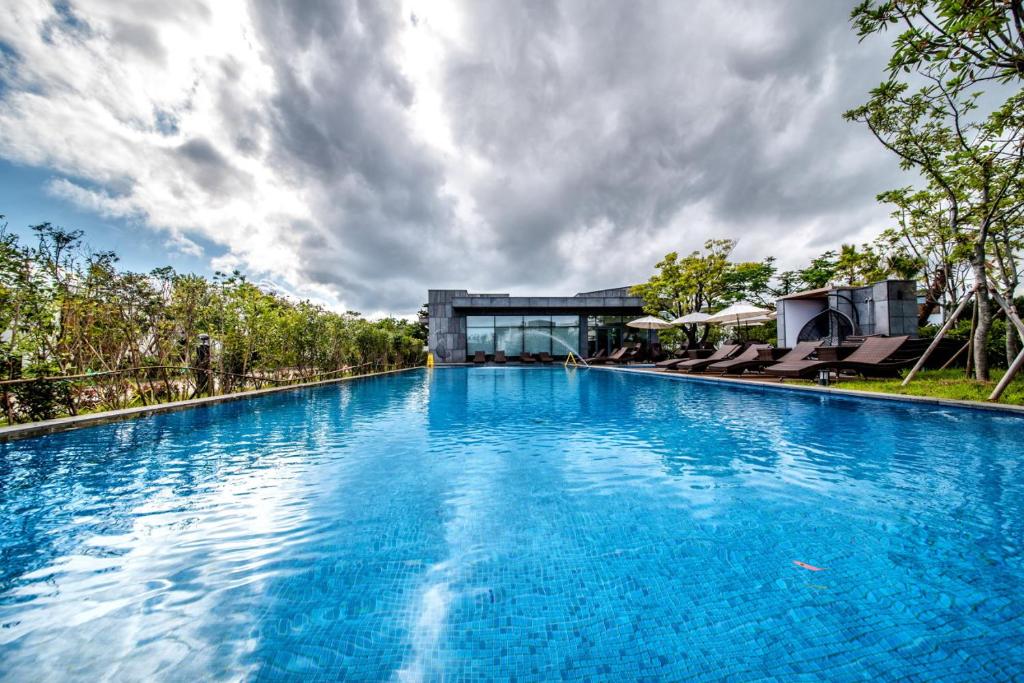 a large pool with blue water in front of a building at The Shimpang Spa & Poolvilla in Seogwipo