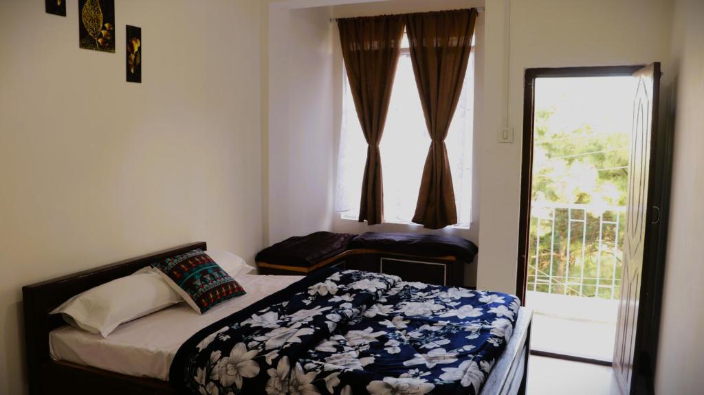 um pequeno quarto com uma cama e uma janela em Yashav Homestay em Shillong