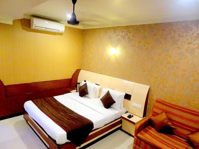 een slaapkamer met een groot bed en een bank bij HOTEL VISHAL PLAZA in Puri