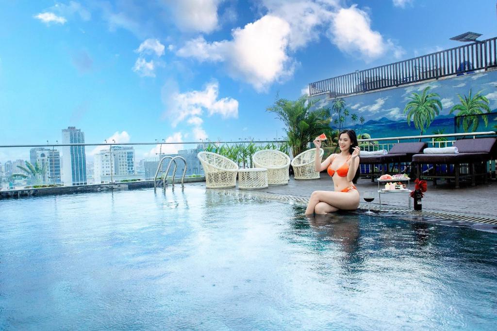 een vrouw in bikini zittend in een zwembad bij Dylan Hotel Danang in Da Nang