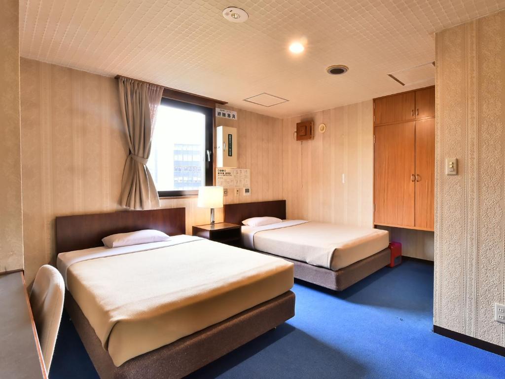 東京にあるホテル観月荘のベッドが2つと窓があるホテルの部屋