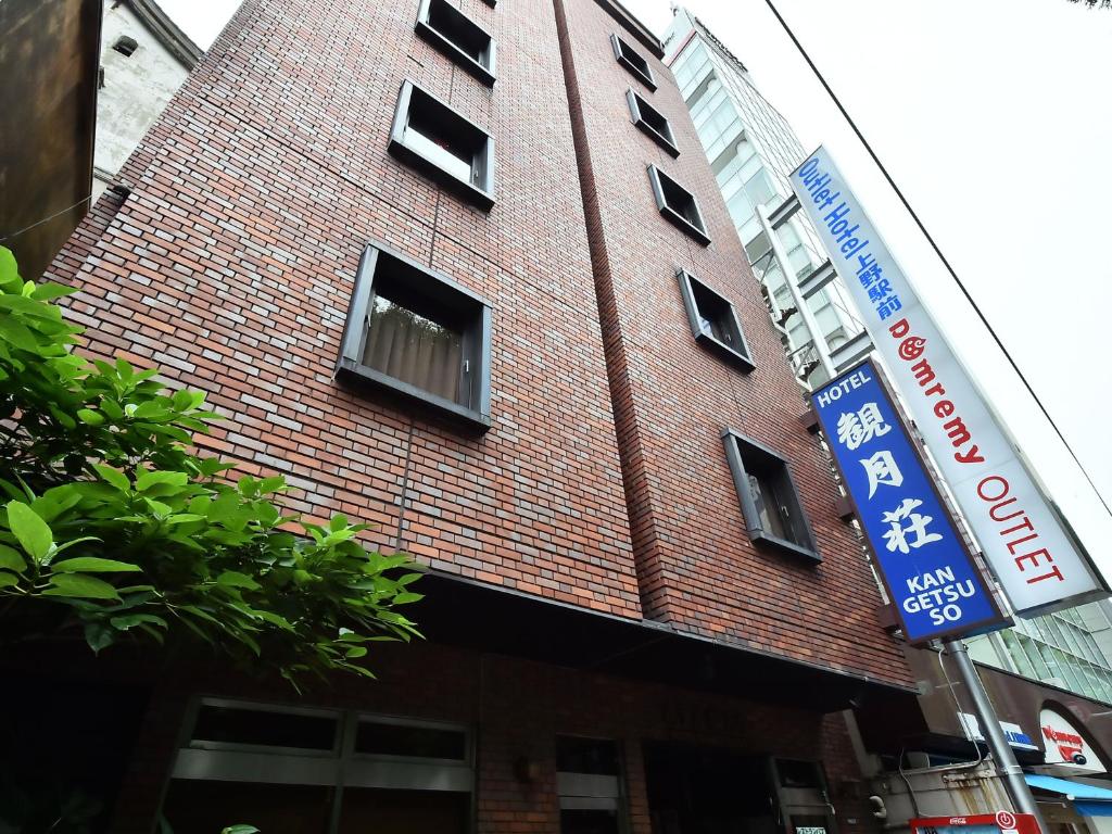 a red brick building with windows and a blue sign at Hotel Kangetsuso in Tokyo