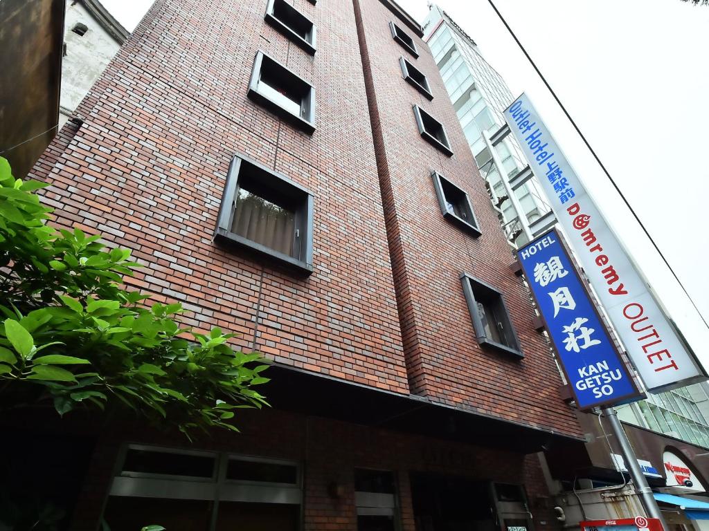 un edificio de ladrillo rojo con ventanas y una señal azul en Hotel Kangetsuso, en Tokio