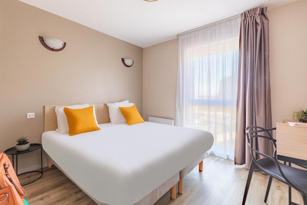 a large bed in a room with a large window at Appart'City Classic Arlon - Porte du Luxembourg in Arlon