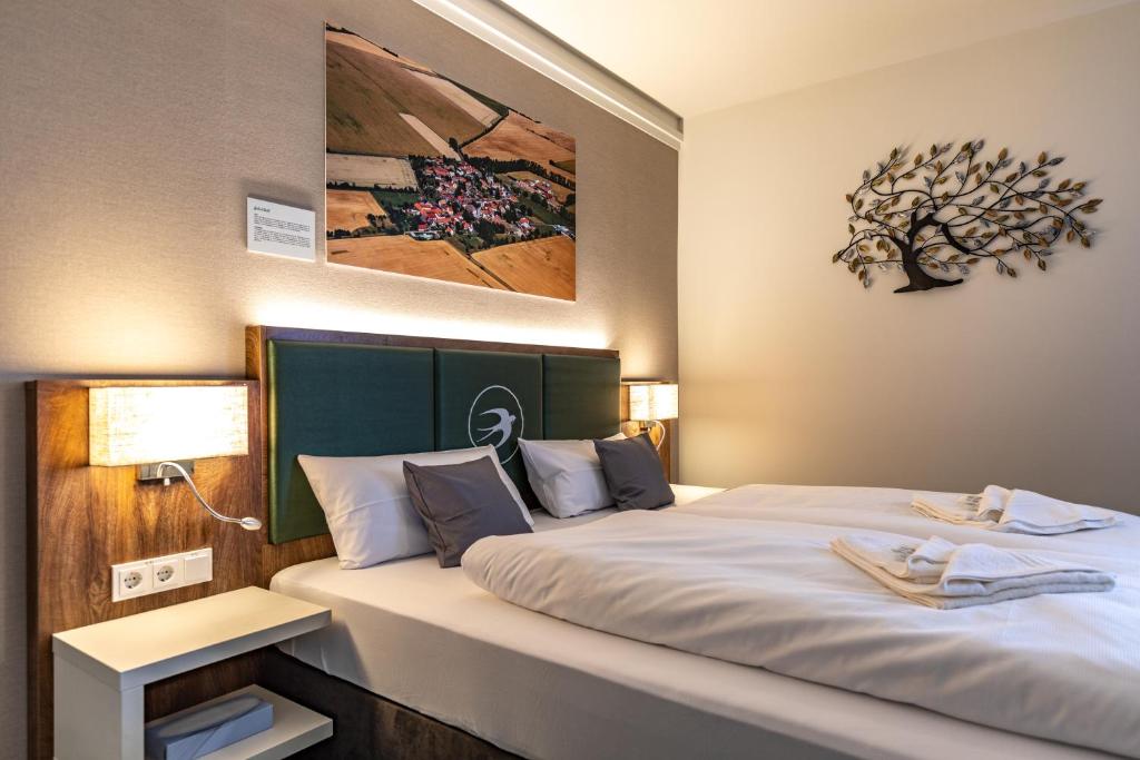 ein Schlafzimmer mit einem großen Bett mit weißer Bettwäsche in der Unterkunft Pension Schwalbennest in Bösleben-Wüllersleben
