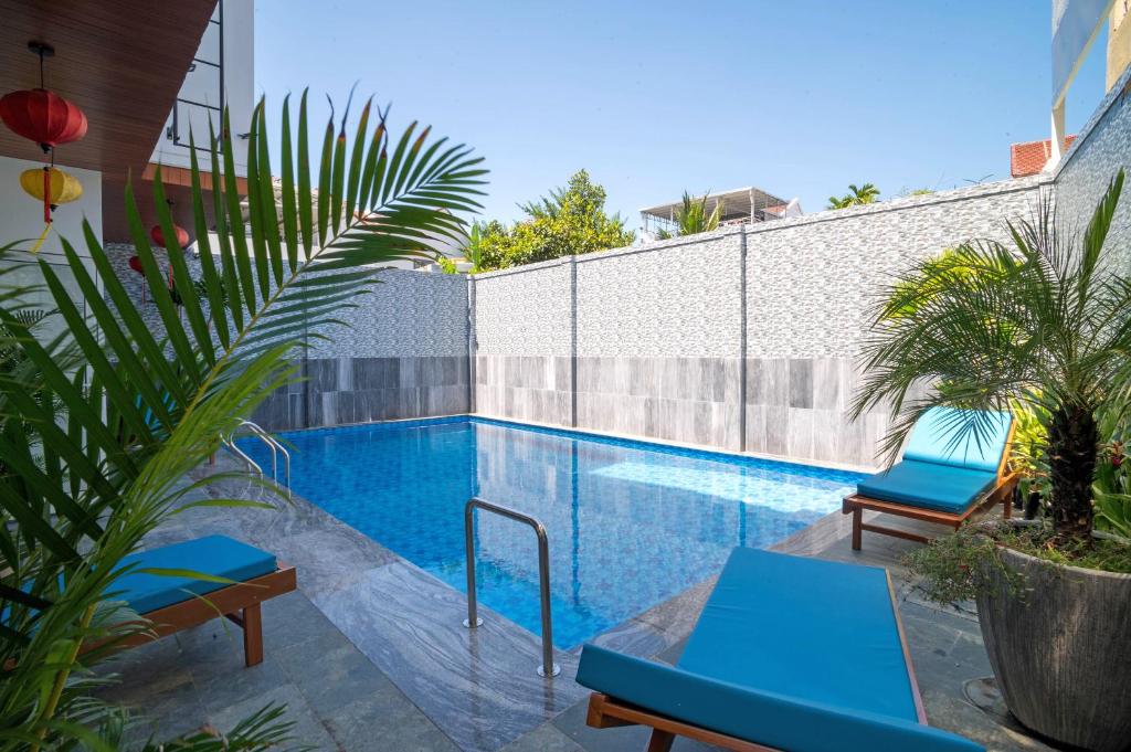 una piscina con 2 sillas azules junto a una valla en White House Central Villa en Hoi An