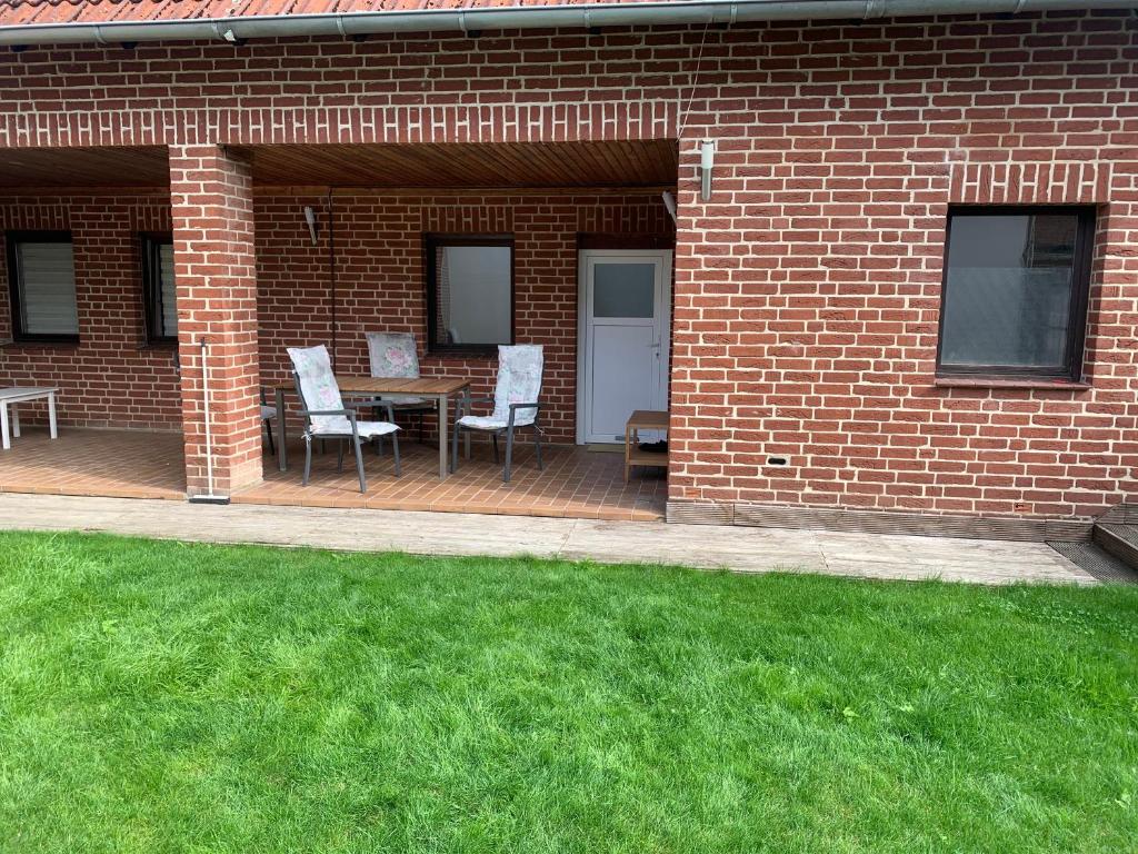 patio ze stołem i krzesłami oraz ceglaną ścianą w obiekcie melissa w mieście Wittingen