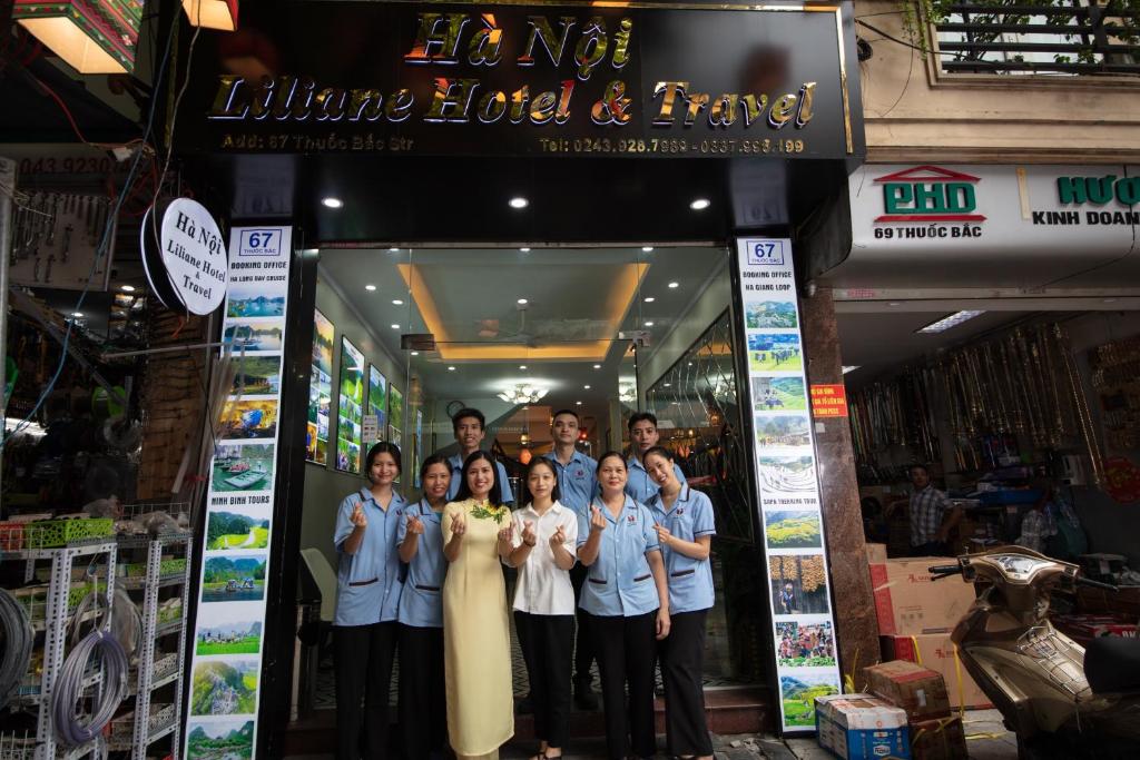 um grupo de pessoas em pé em frente a uma loja em Hanoi Liliane Hotel and Travel em Hanói