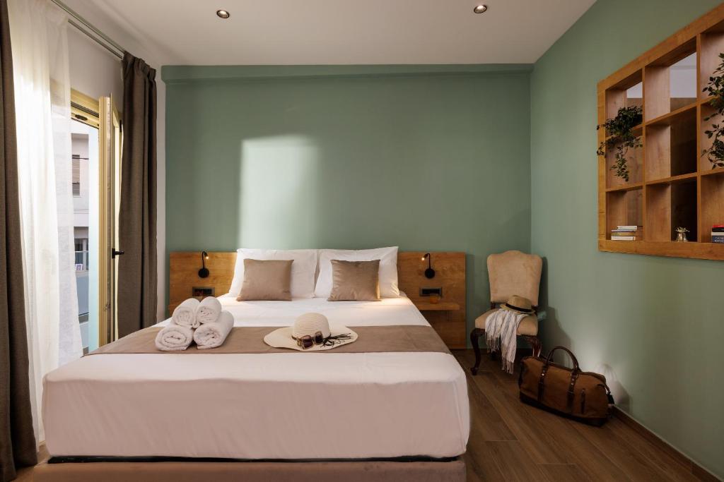 1 dormitorio con 1 cama con 2 sombreros y toallas en Cathedral Suites en Heraclión
