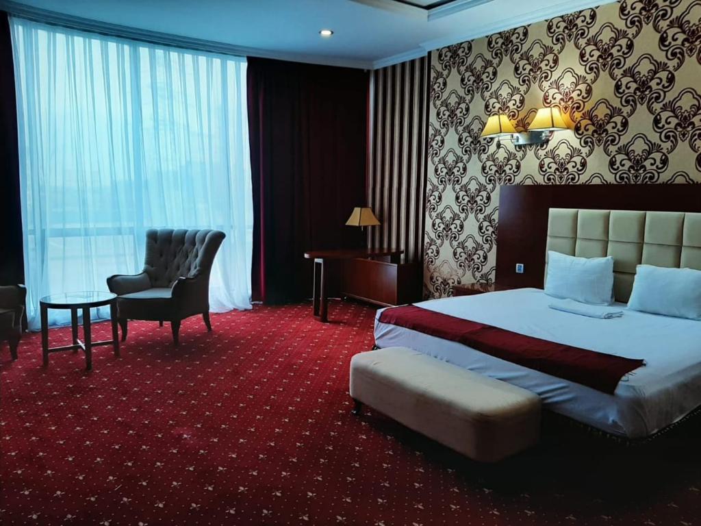 バクーにあるEmeraldGoldの大きなベッドと椅子が備わるホテルルームです。