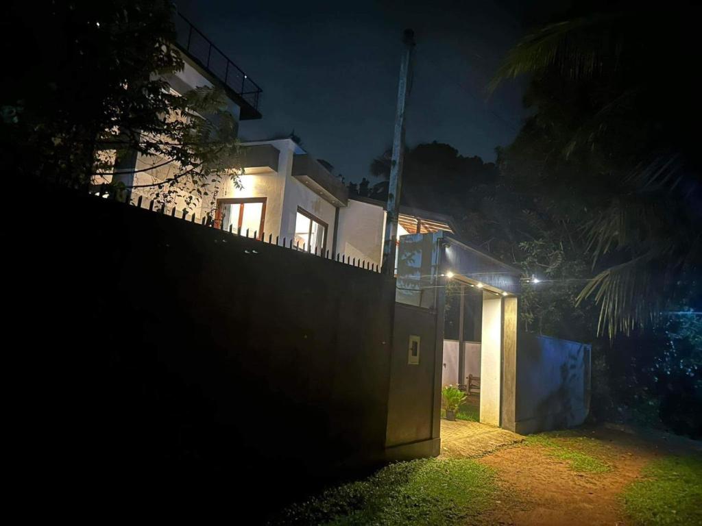 a house lit up at night with a fence at SOHA Home Stay in Galle