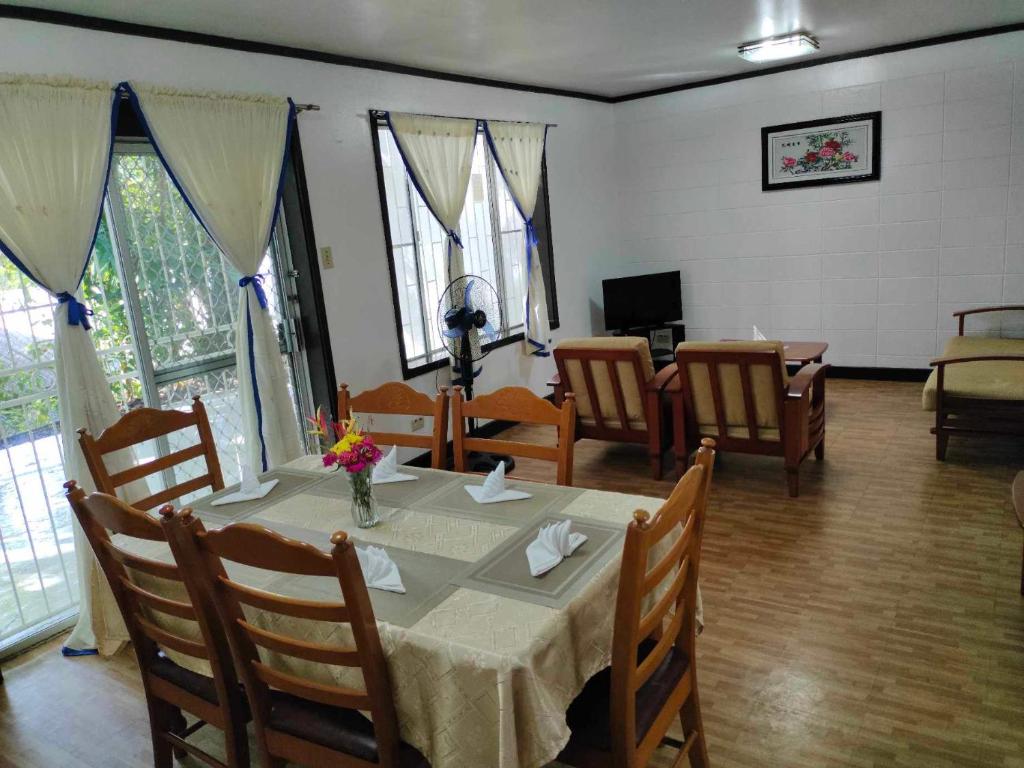 comedor con mesa, sillas y ventanas en Tropical Paradise Retirement Village, Inc., en Sawat