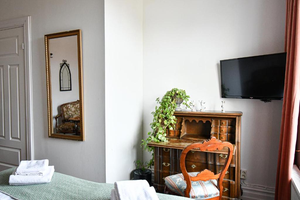 Habitación con TV, silla y espejo. en Prins Carl en Ystad