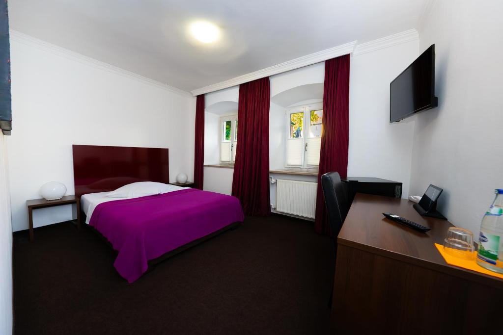 a bedroom with a purple bed and a desk at Hotel Bergbauer in Neuburg an der Donau