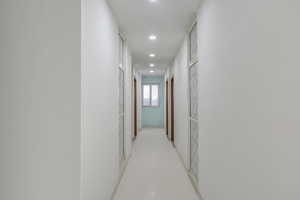 an empty corridor with white walls and an open door at Collection O 83129 Hotel Galaxy Hospitality in Kharadi