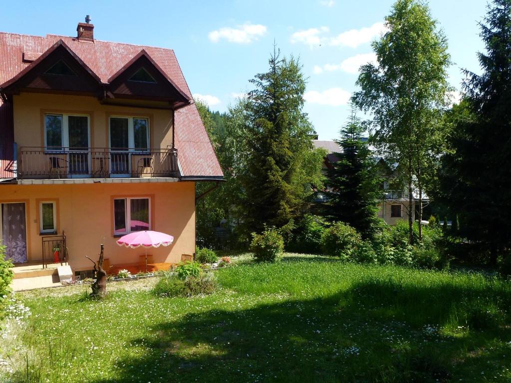 una casa con un paraguas rosa en un patio en Pokoje Gościnne Vida, en Krynica-Zdrój