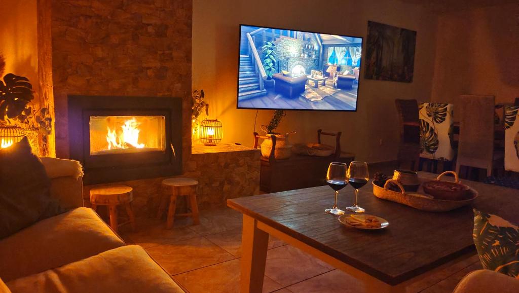 a living room with a fireplace and two glasses of wine at Lia y el Pinar in Olías del Rey