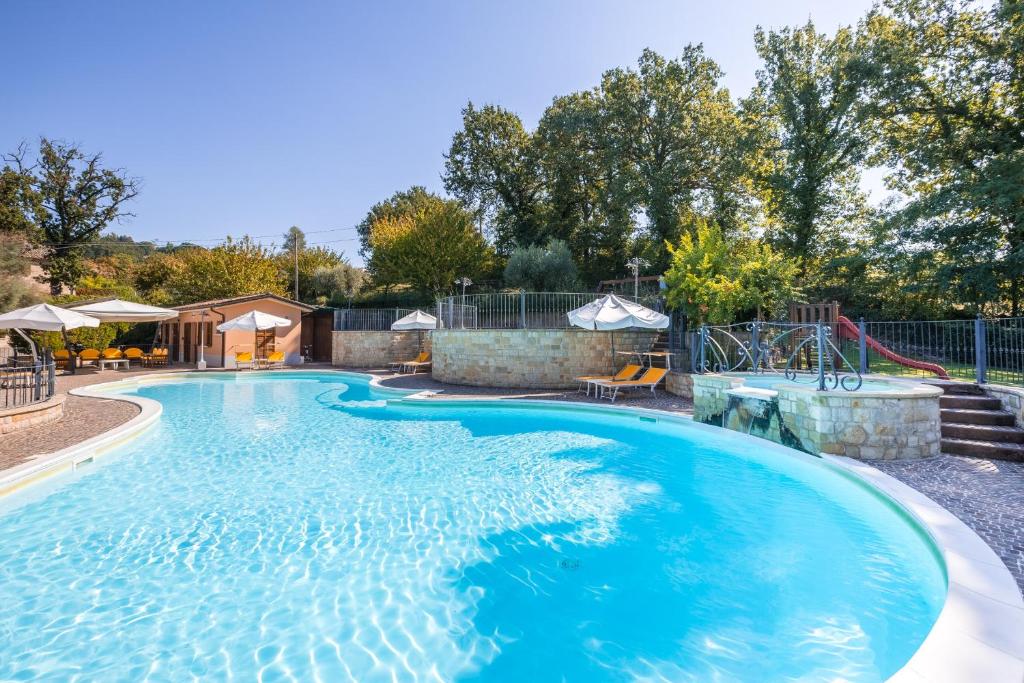 una gran piscina con agua azul en un patio en Tenuta Le Fontanelle, en SantʼIppolito
