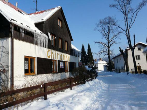 a building with a fence in the snow at Chalupa Chiranka in Lipova Lazne