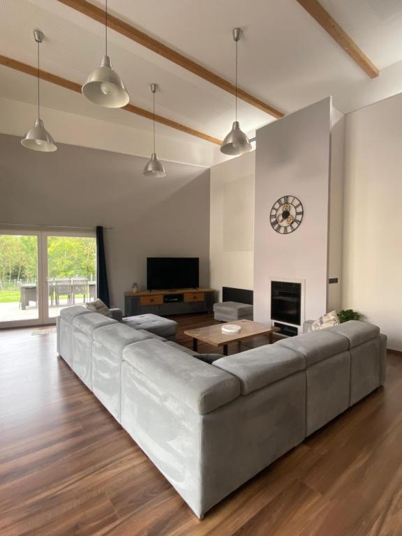 a living room with a large couch and a tv at Grange rénovée esprit loft Côte d&#39;Opale in Wierre-Effroy