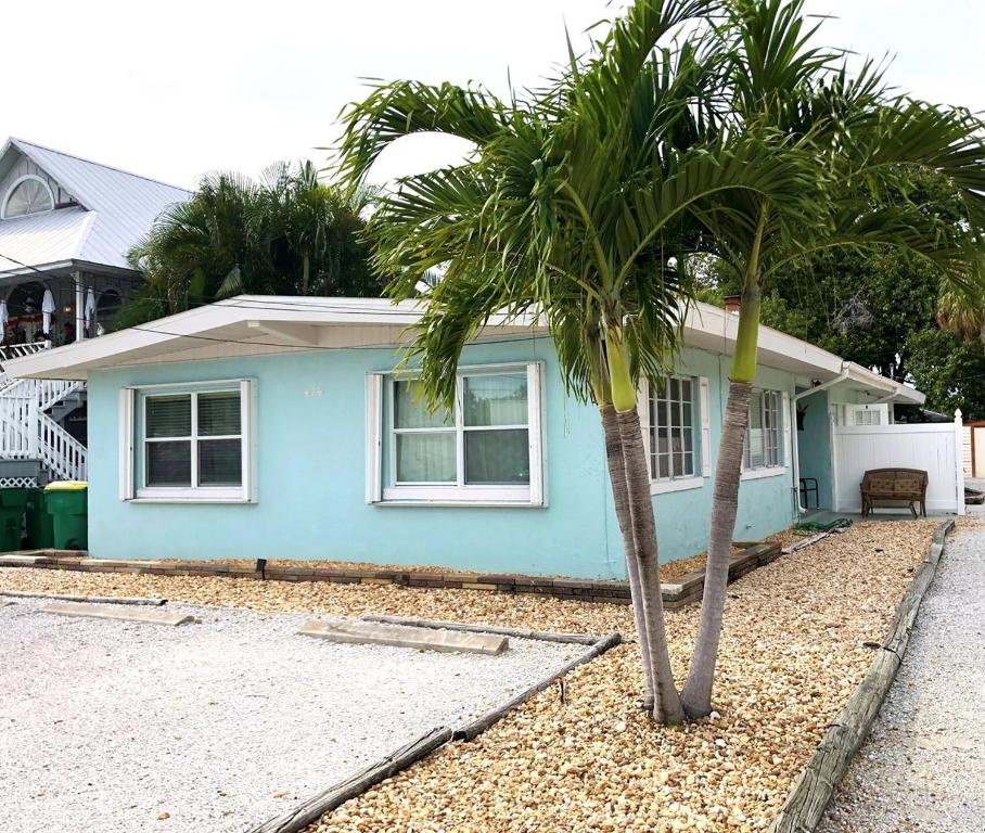 a blue house with two palm trees in front of it at Island Gem A home in Anna Maria