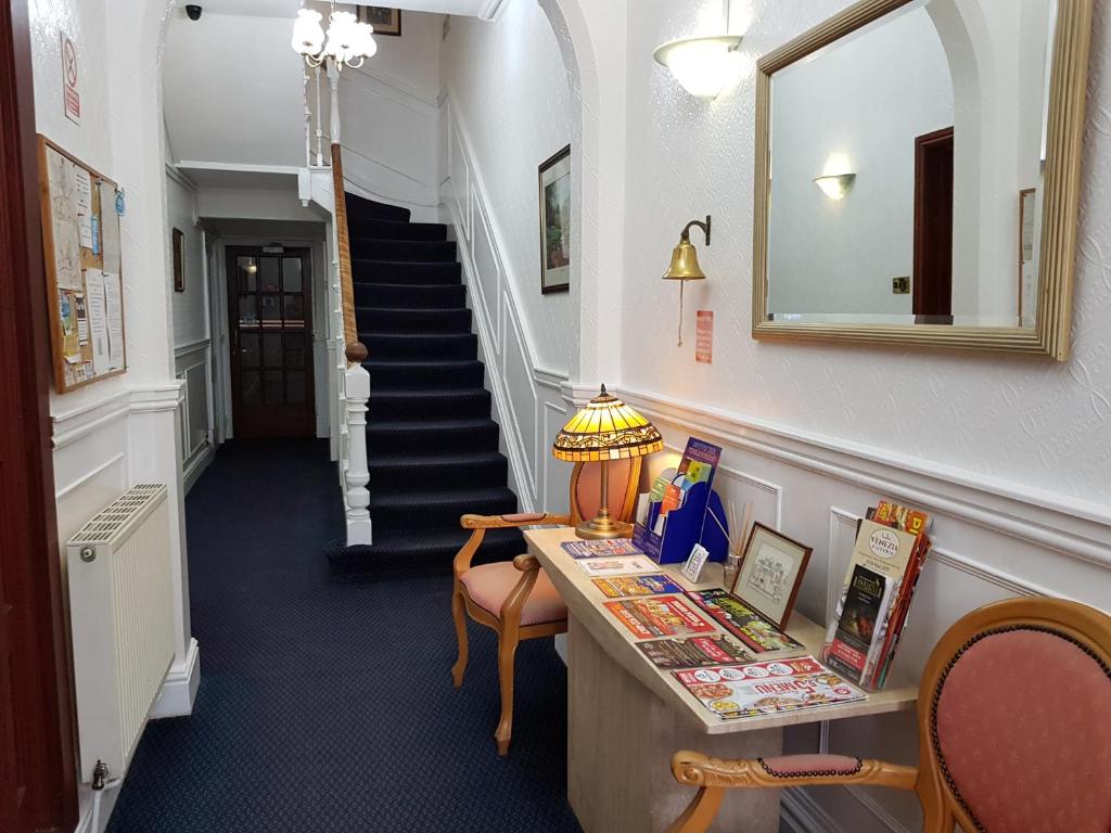 a hallway with a staircase with a desk and a mirror at Fairhaven Guest Accommodation in Nottingham
