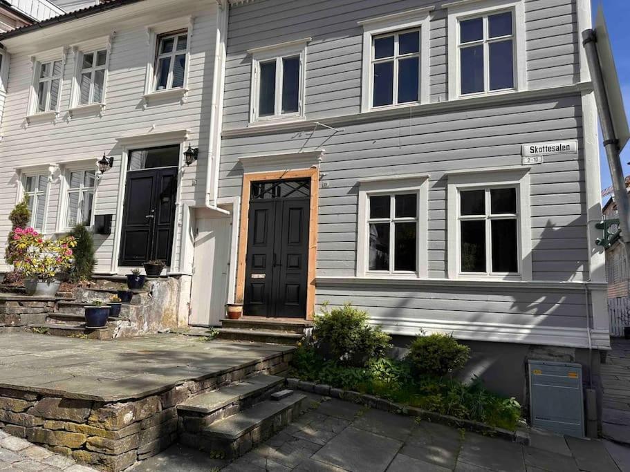 uma casa cinzenta com uma porta preta e uma entrada de pedra em Koslig leilighet i Bergens smørøye em Bergen
