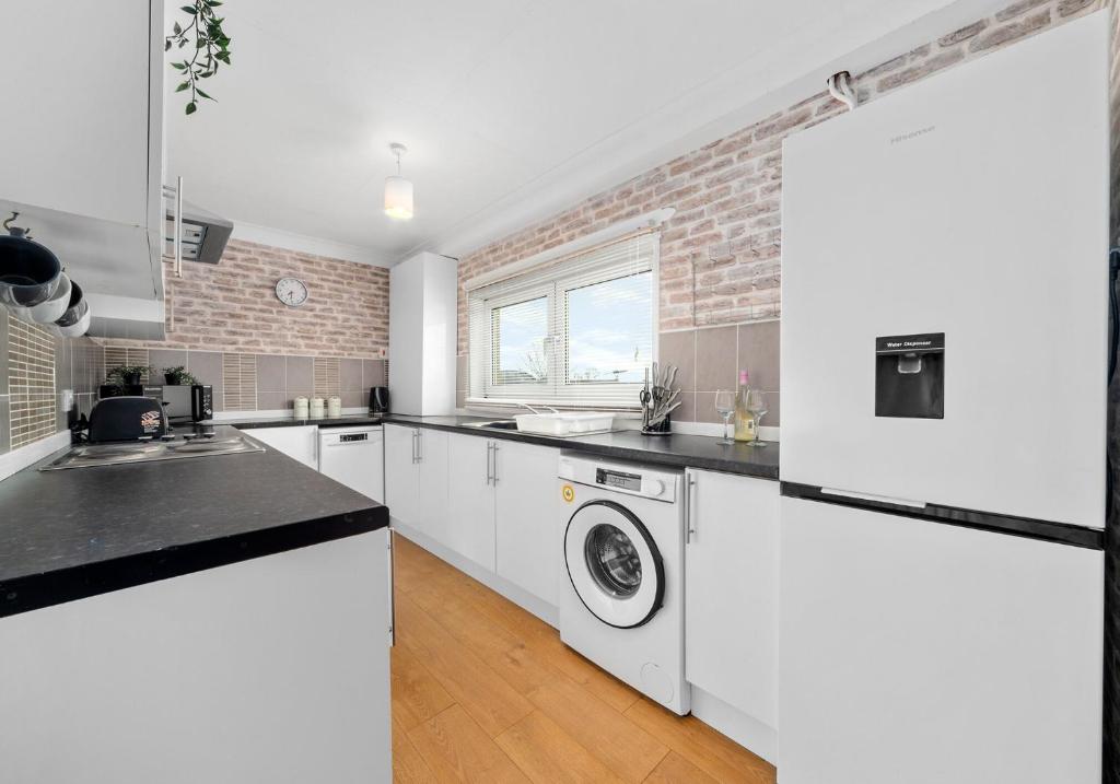 a kitchen with white appliances and a brick wall at Berwick Apartment by Klass Living Coatbridge in Coatbridge