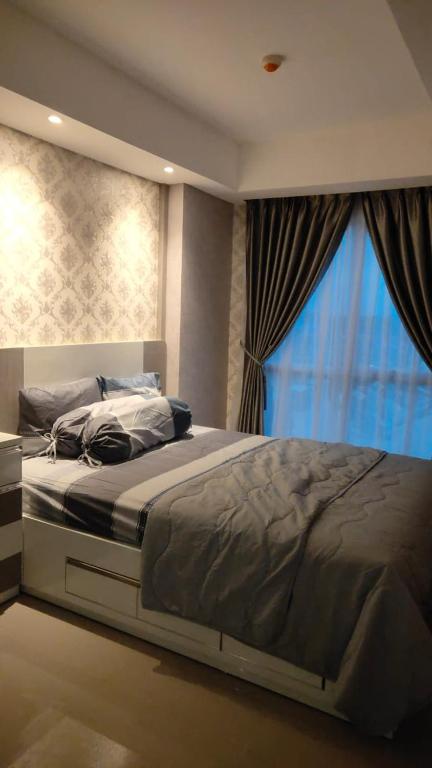 a large bed in a bedroom with a window at Apartemen Skylounge Makassar in Sudiang