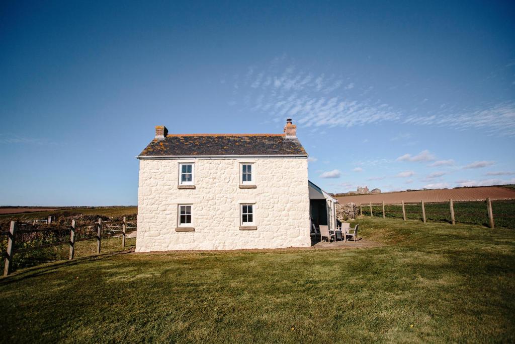 a white brick building on a grass field at Faraway Cottage in Penzance