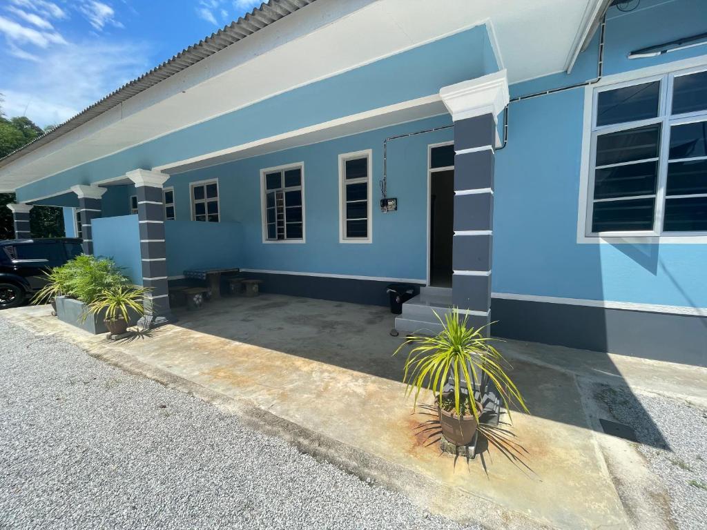 una casa azul con macetas delante de ella en D'PAYA HOMESTAY, en Bachok