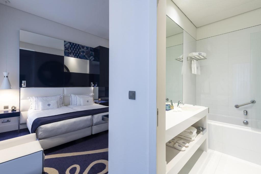 Portugal Boutique Hotel في لشبونة: غرفة نوم مع سرير وحوض استحمام ومغسلة