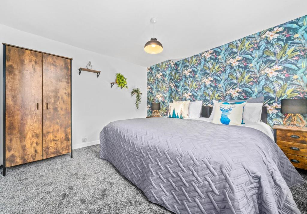 a bedroom with a large bed and a floral wall at West End House by Klass Living Bellshill in Bellshill