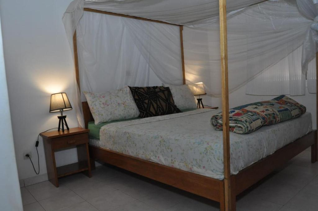 a bedroom with a canopy bed with two lamps at Appartement à Saly in Saly Portudal