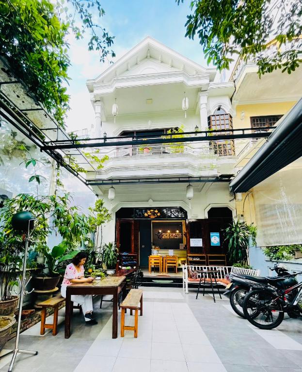 a person sitting at a table outside of a building at SHARK HOSTEL in Hue