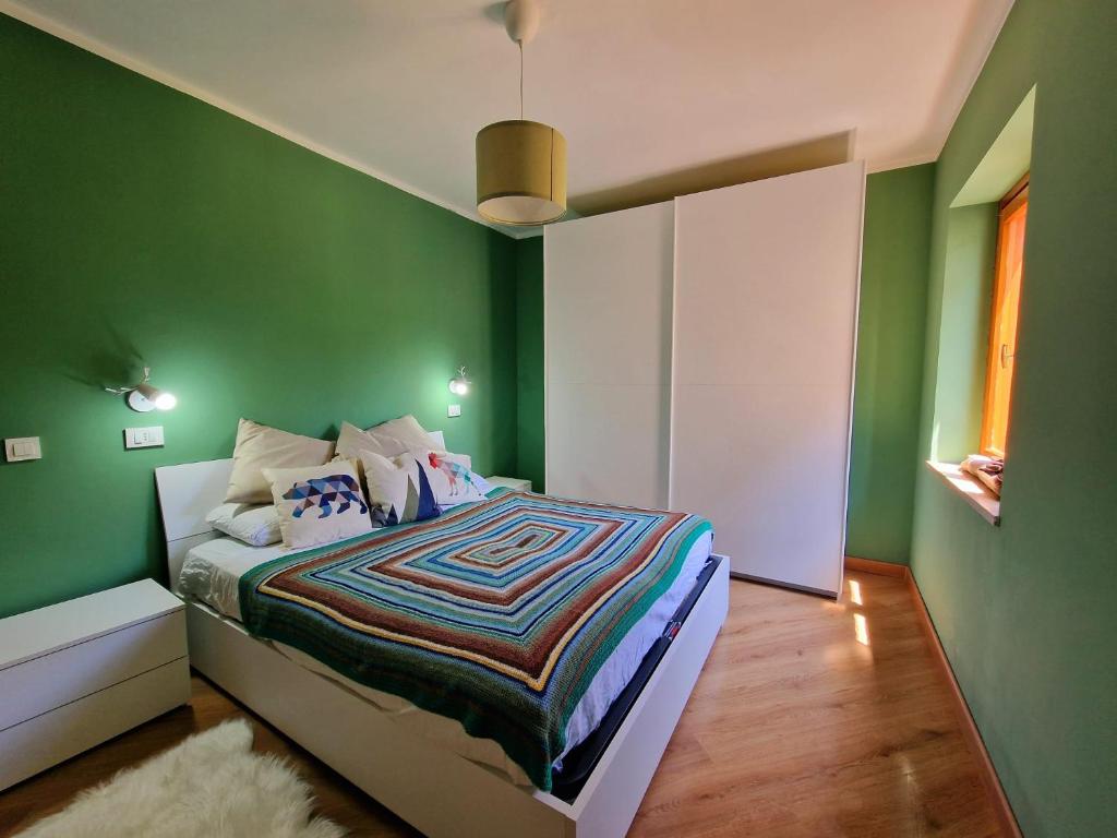 una camera da letto con pareti verdi e un letto con un piumone di WH-Bilocale Green Roburent a San Giacomo