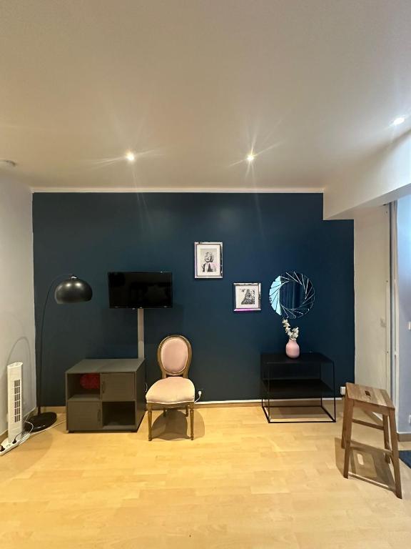 a living room with a blue wall and a chair at charmant 2 pièces sur deux niveaux in Paris
