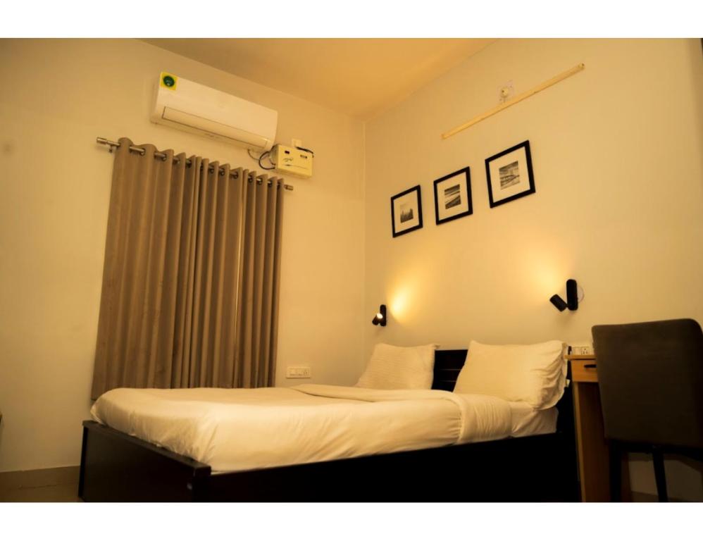 ブバネーシュワルにあるMy Homes and Hotels, Bhubaneswar, Odishaのベッドルーム1室(白いシーツとデスク付)
