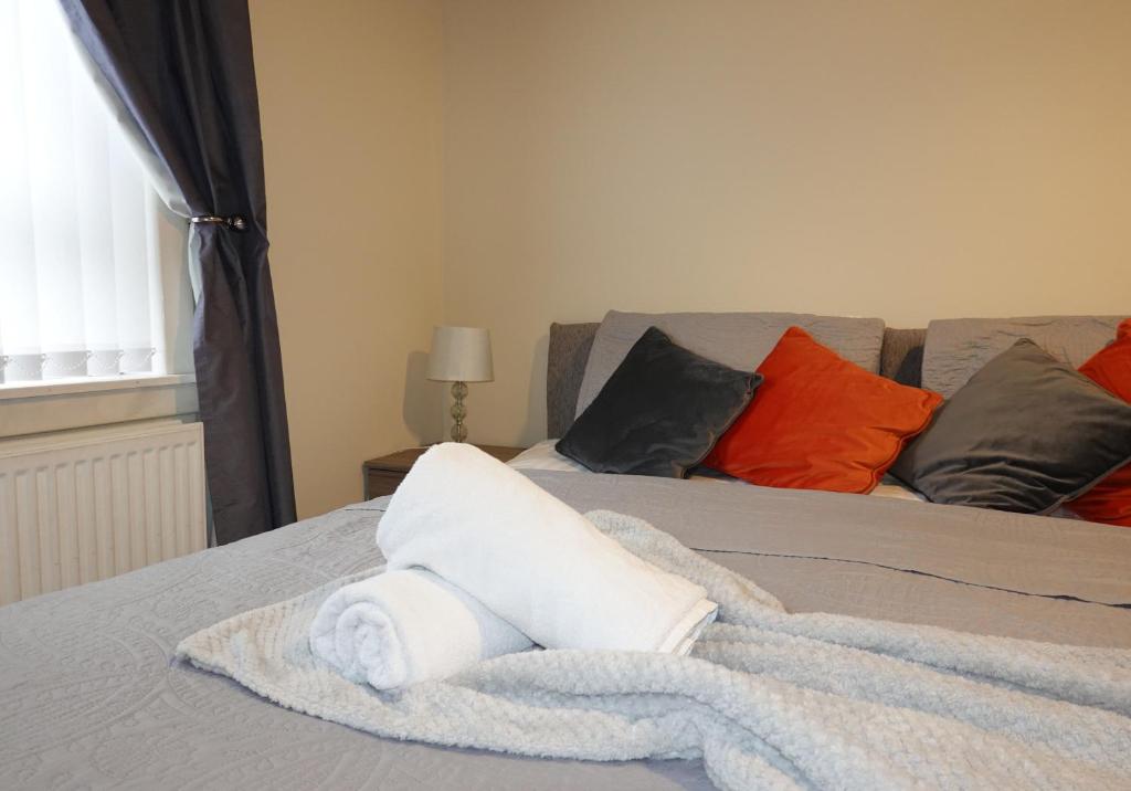 - une serviette blanche roulée assise sur un lit dans l'établissement Welsh Drive Apartment by Klass Living Blantyre, à High Blantyre