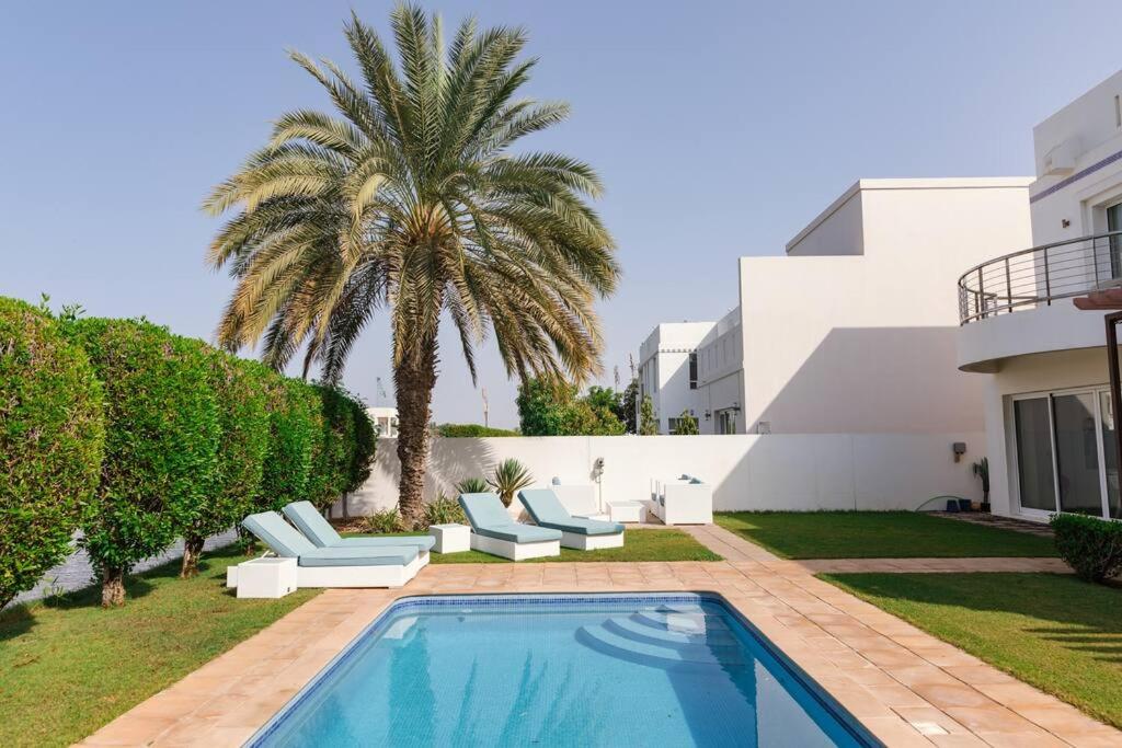 a villa with a swimming pool and a palm tree at Private 5 Bed Villa / Next to Lagoon in Seeb